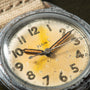 Vintage Elgin watch with cream dial, Arabic numerals, and brown leather strap showing visible patina and wear.