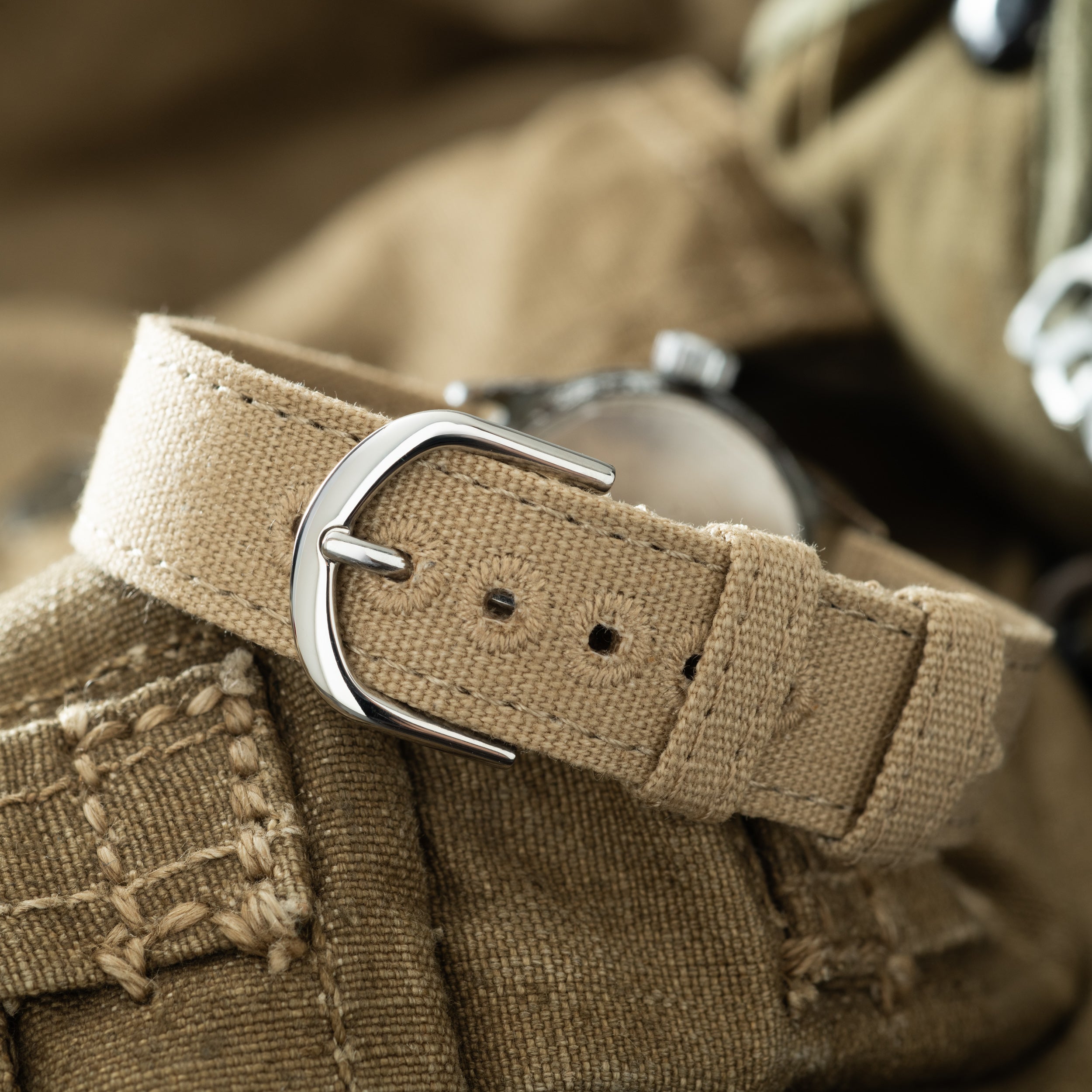 Elgin USMC watch with tan canvas strap and silver buckle displayed on khaki fabric.