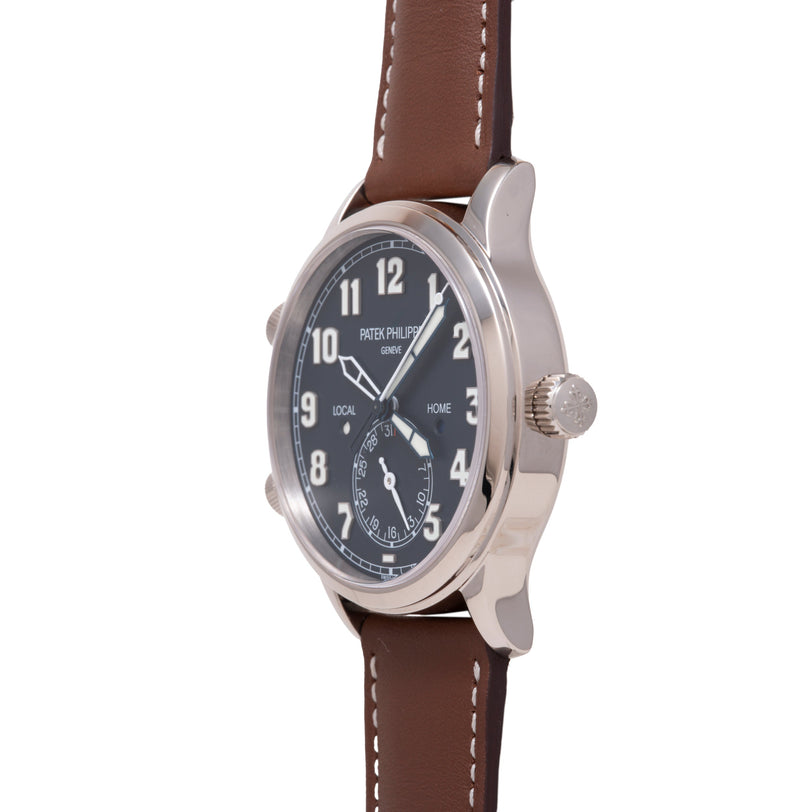 Silver stainless steel watch with black dial, brown leather strap, dual time zones marked "Local" and "Home," and small secon