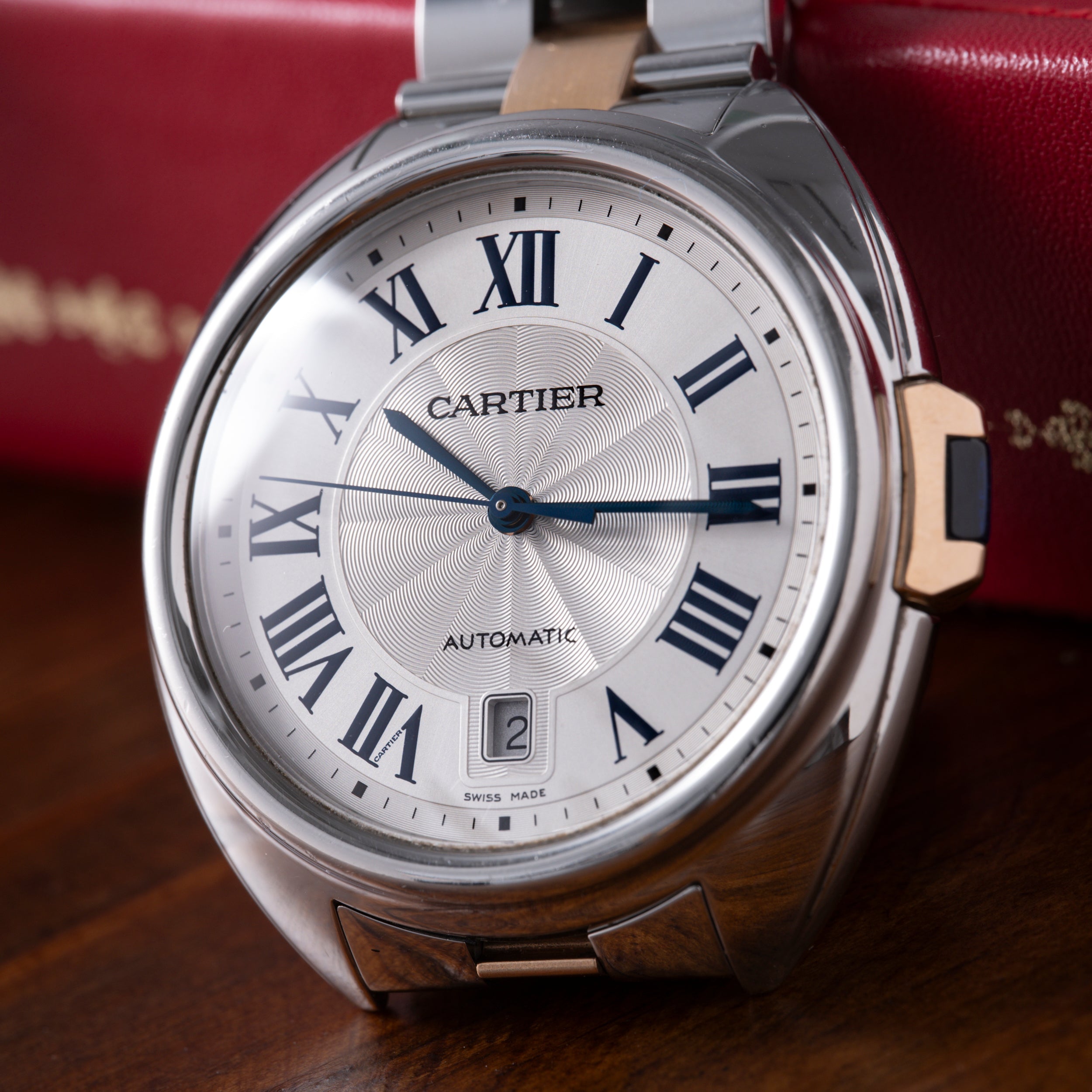 Cartier Clé de Cartier automatic watch with silver case, two-tone bracelet, white dial, and Roman numerals.