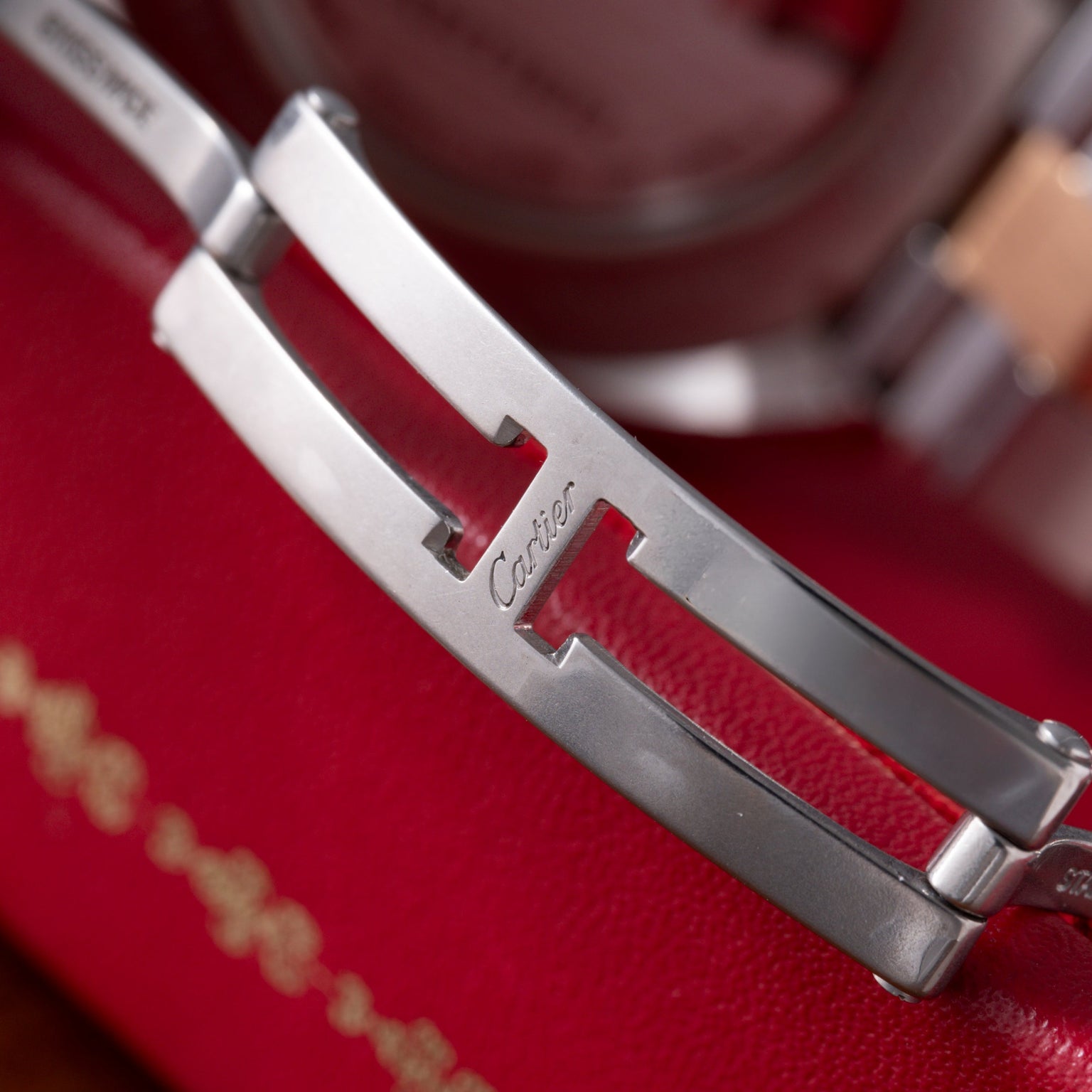 Silver-tone metal bracelets with red leather inlay and Cartier engraving on curved bands.
