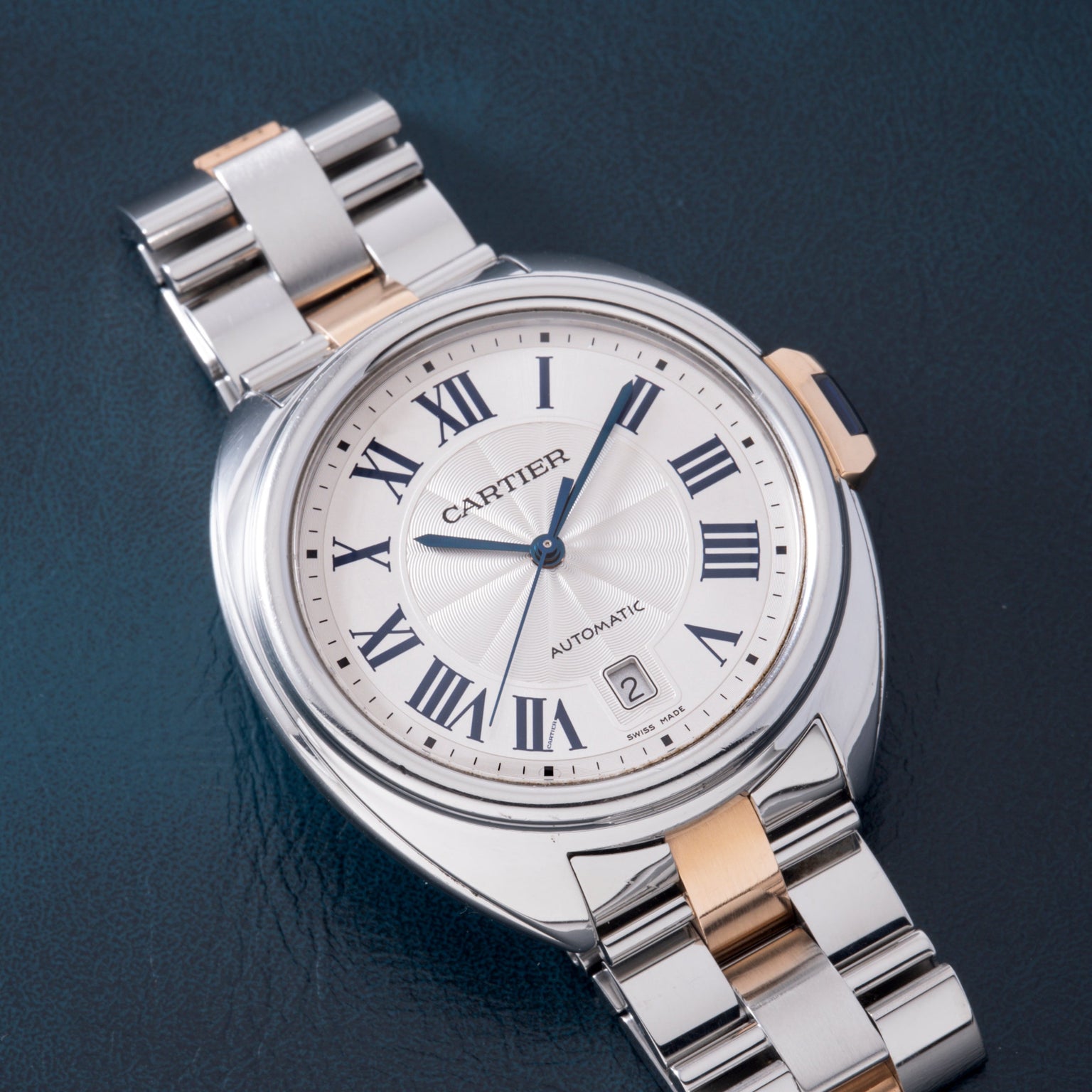 Cartier watch with silver and rose gold two-tone bracelet, white dial with Roman numerals, and date window.
