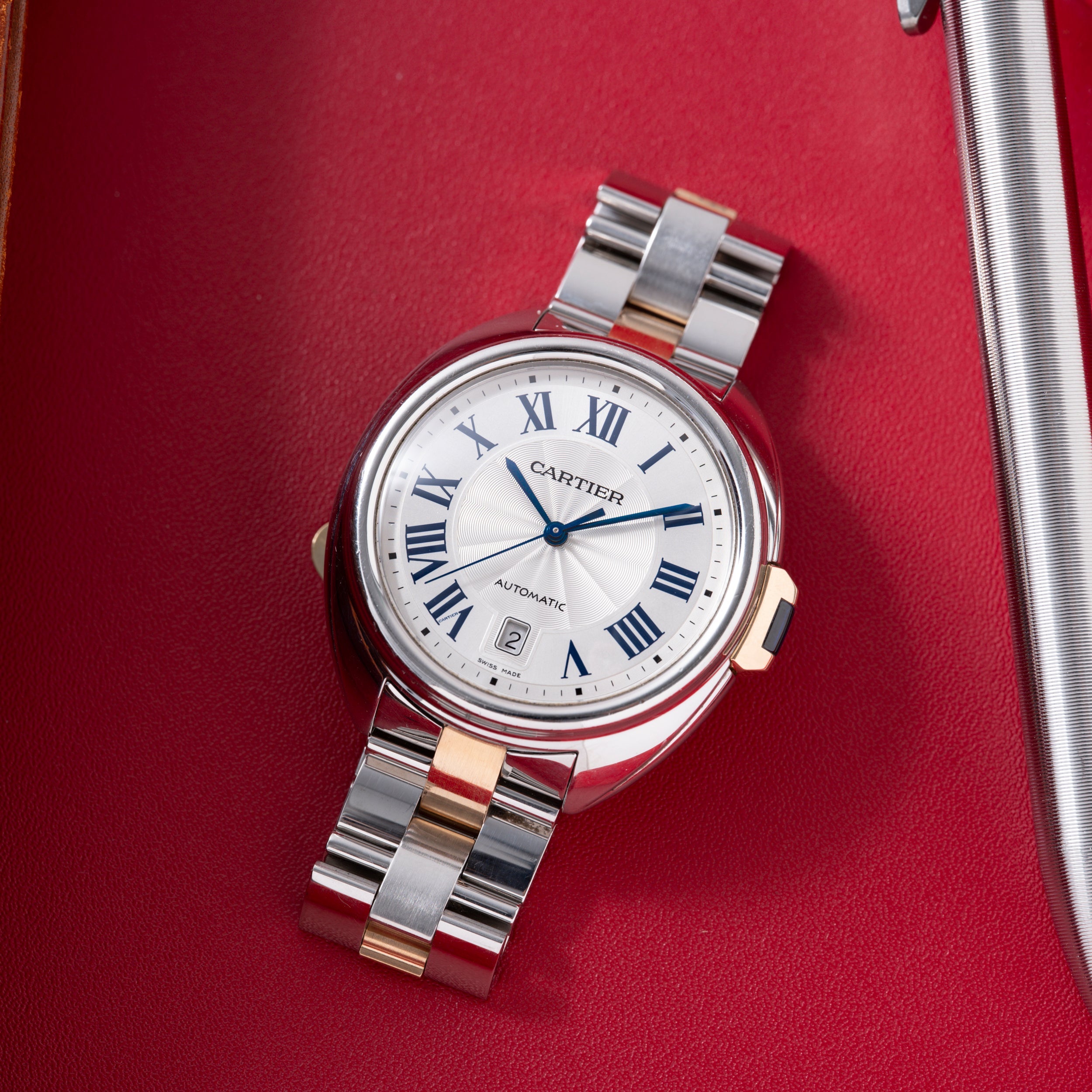 Cartier Clé de Cartier automatic watch with white dial, Roman numerals, steel and rose gold two-tone bracelet on red fabric b