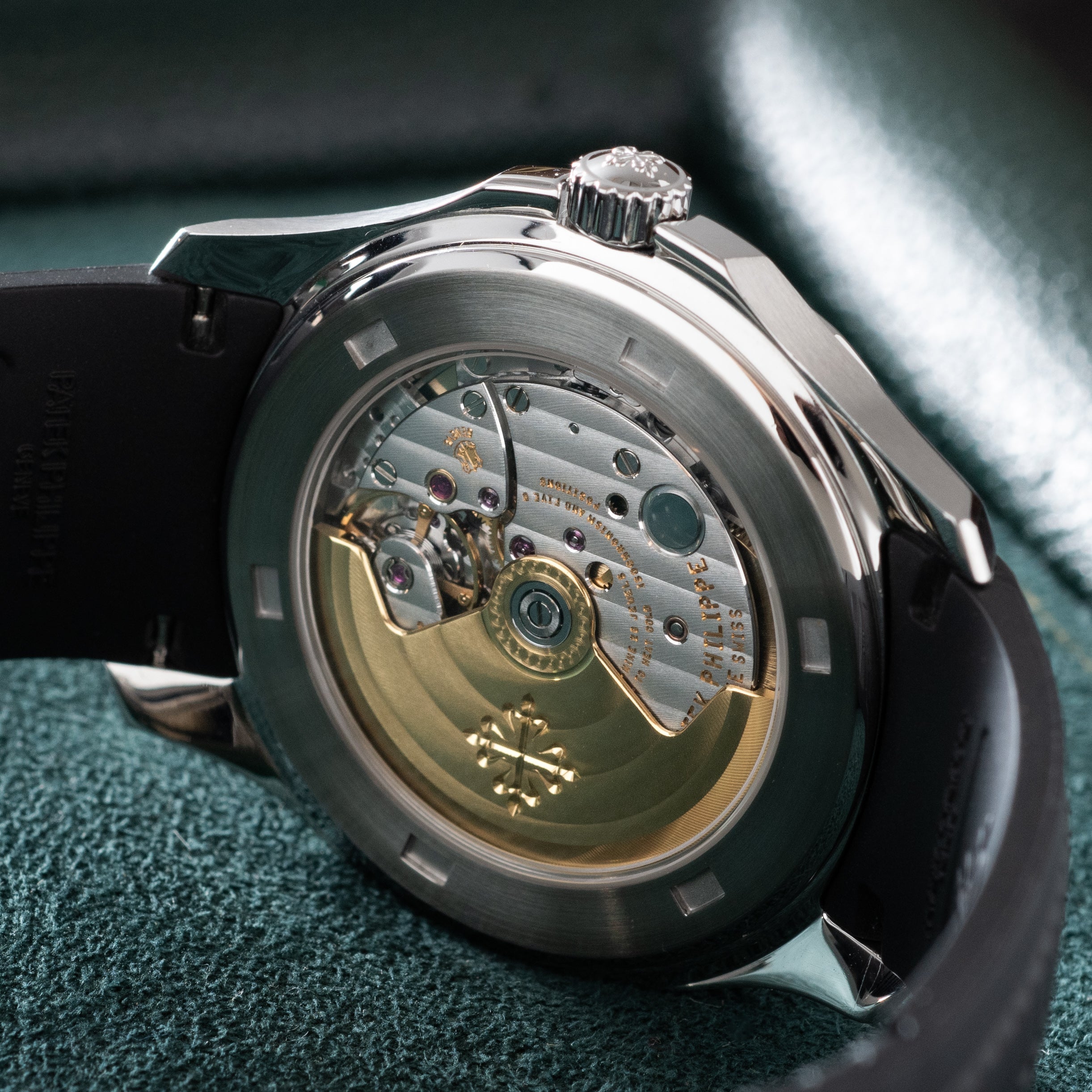 Stainless steel watch with visible mechanical movement through transparent caseback, black rubber strap, and crown on polishe