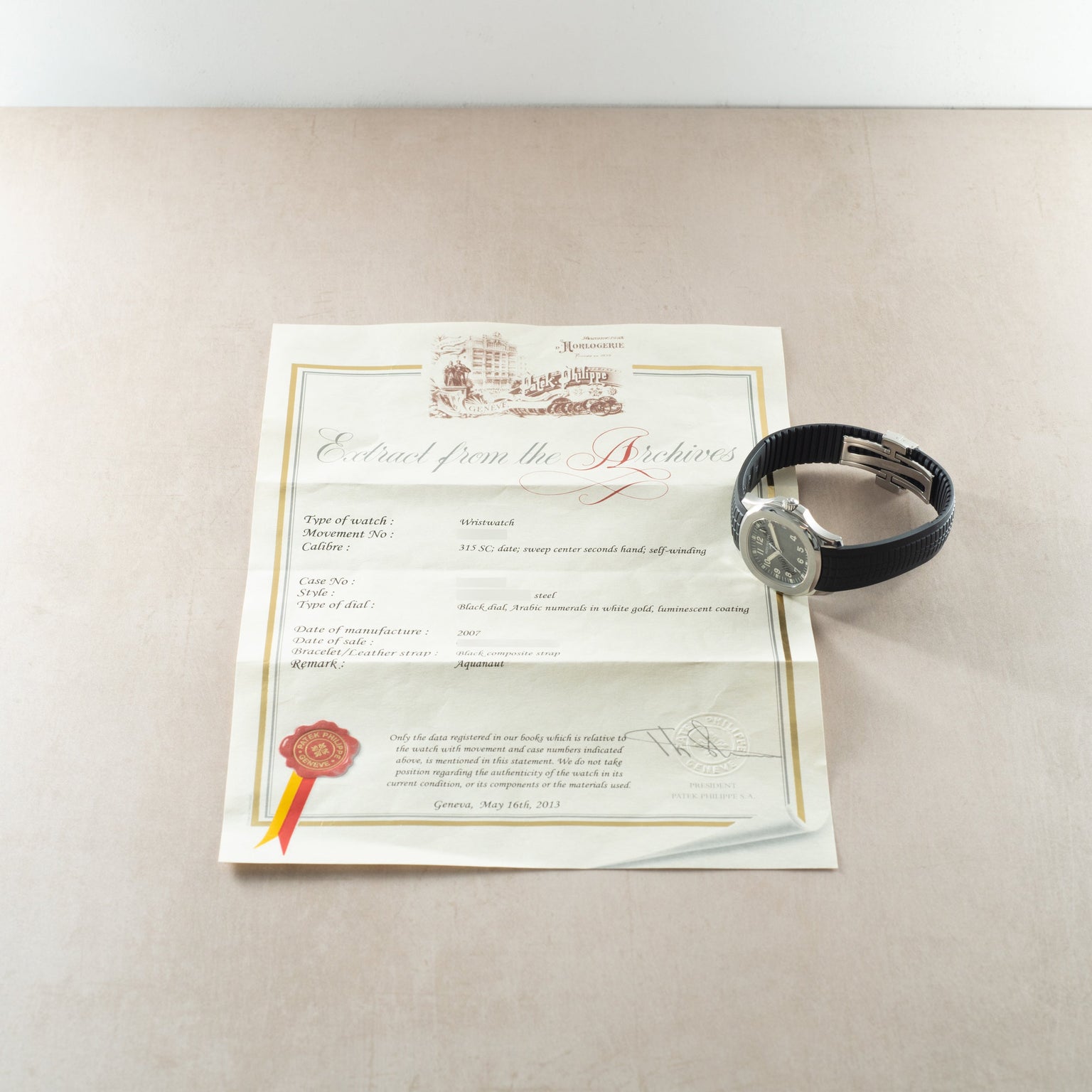 Patek Philippe Aquanaut watch with black rubber strap and silver dial displayed with certificate of authenticity.