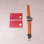 Omega watch with blue dial and orange leather strap, displayed with two red warranty and pictogram cards.