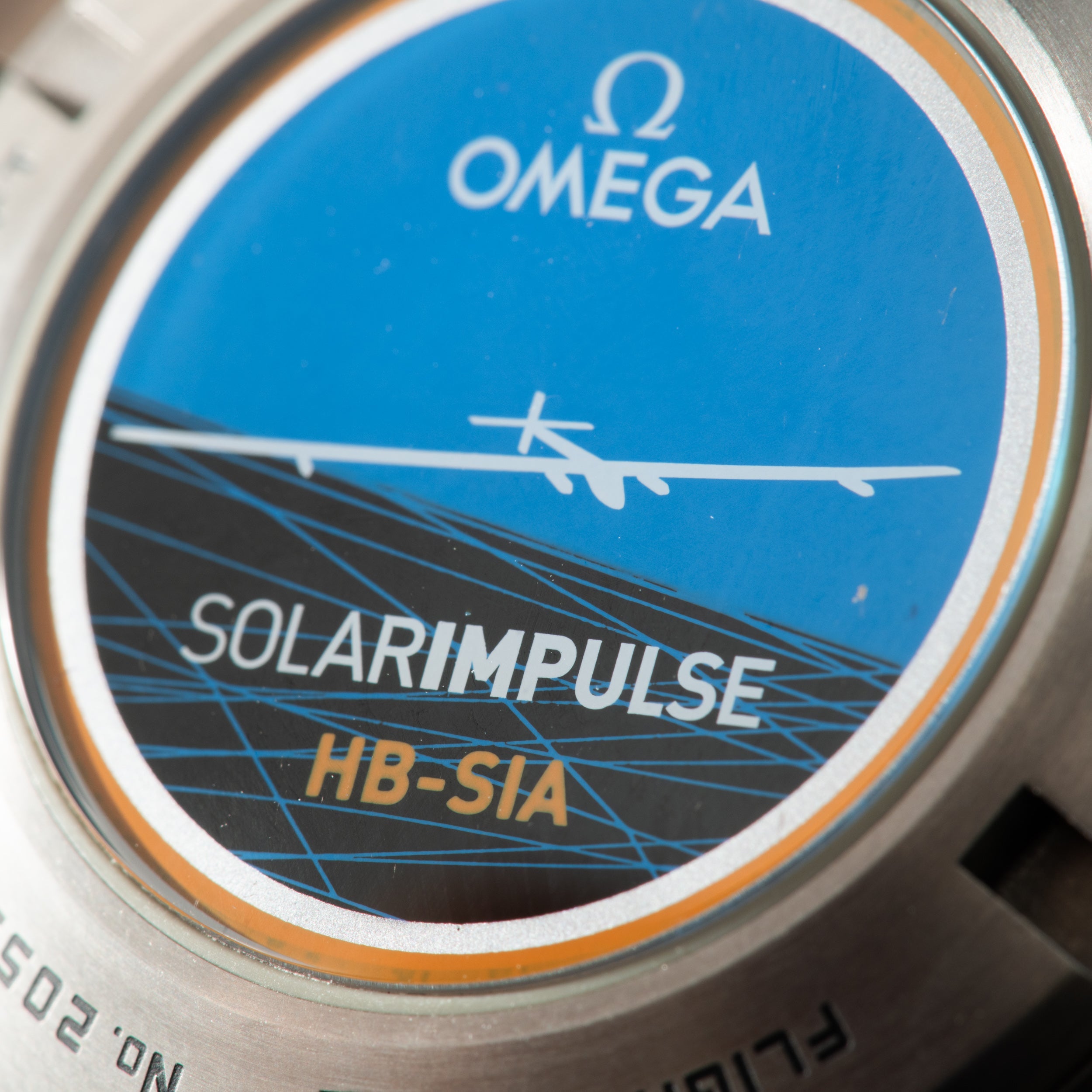 Titanium watch face with blue dial, Omega logo, Solar Impulse HB-SIA text, and orange accents on bezel.