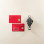 Omega Speedmaster titanium chronograph with black dial and three subdials, displayed with two red warranty cards.