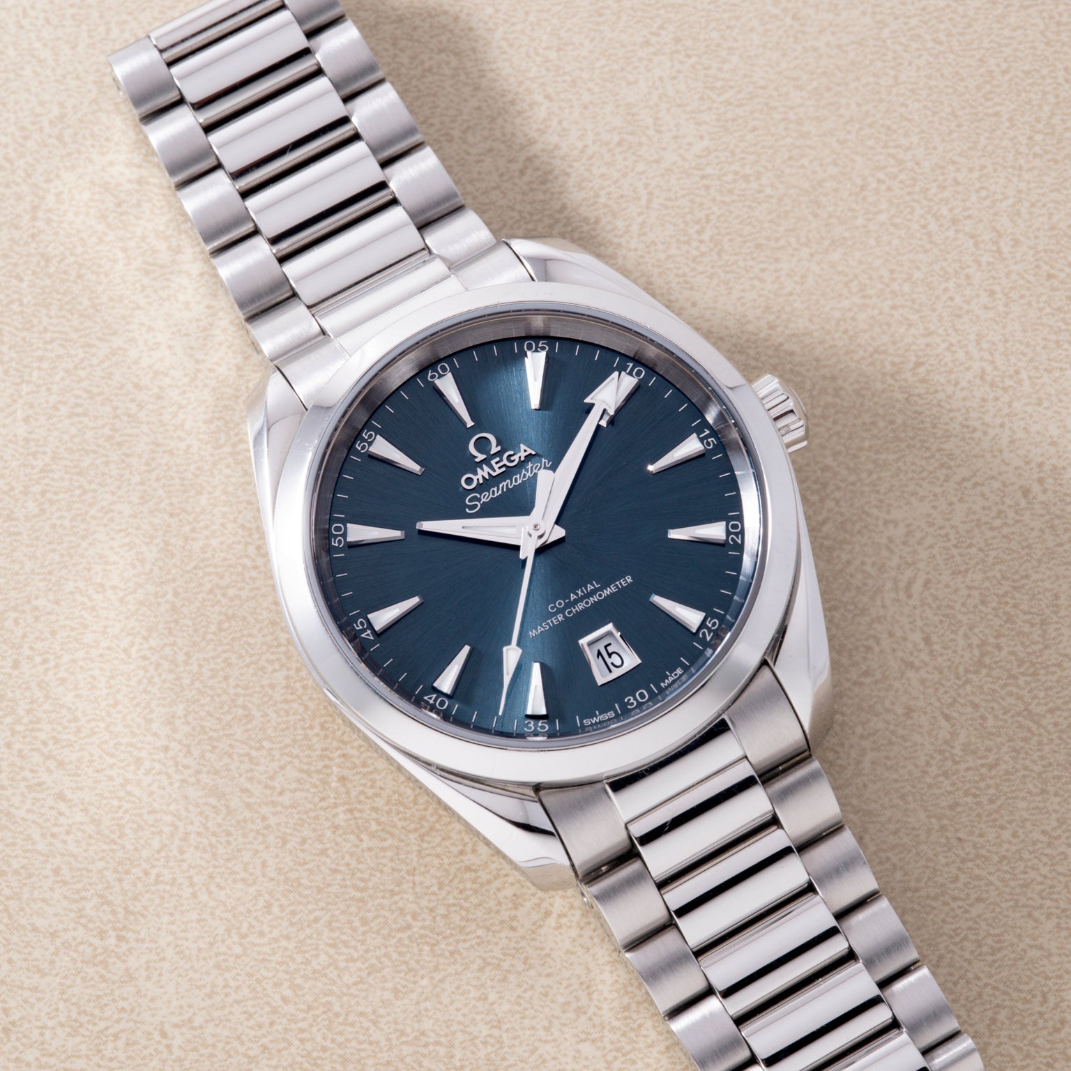Stainless steel watch with dark blue dial, white hour markers and hands, date window, and matching metal bracelet.