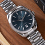 Omega Seamaster watch with dark blue dial, silver-tone stainless steel case and bracelet on wooden surface.