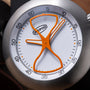 Ikepod Megapod timer with hourglass-shaped orange hands on white dial with numbered minute markings and brushed metal casing.