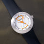 White Ikepod watch with orange hourglass-shaped hands and markers, dark blue rubber strap, stainless steel case.