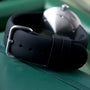 Black Ikepod Duopod watch with silver buckle and white dial model displayed on green surface.