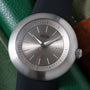 Ikepod Duopod watch with brushed silver case, gray dial, white hour markers, and black leather strap.