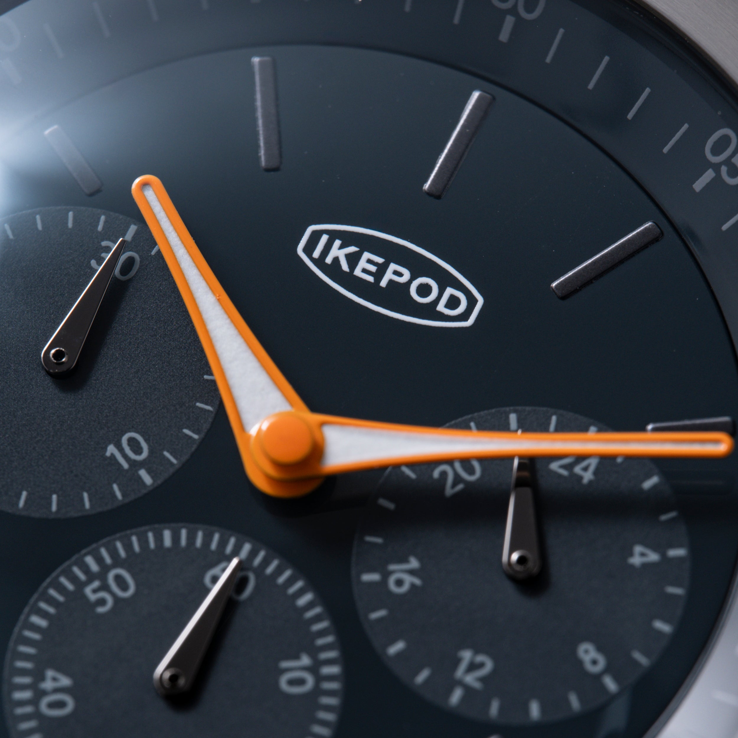 Ikepod Chronopod watch face with dark dial, orange hands, IKEPOD logo, and multiple subdials with hour markers.