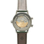 Stainless steel watch with transparent caseback displaying gold movement, green and brown leather strap with Patek Philippe b