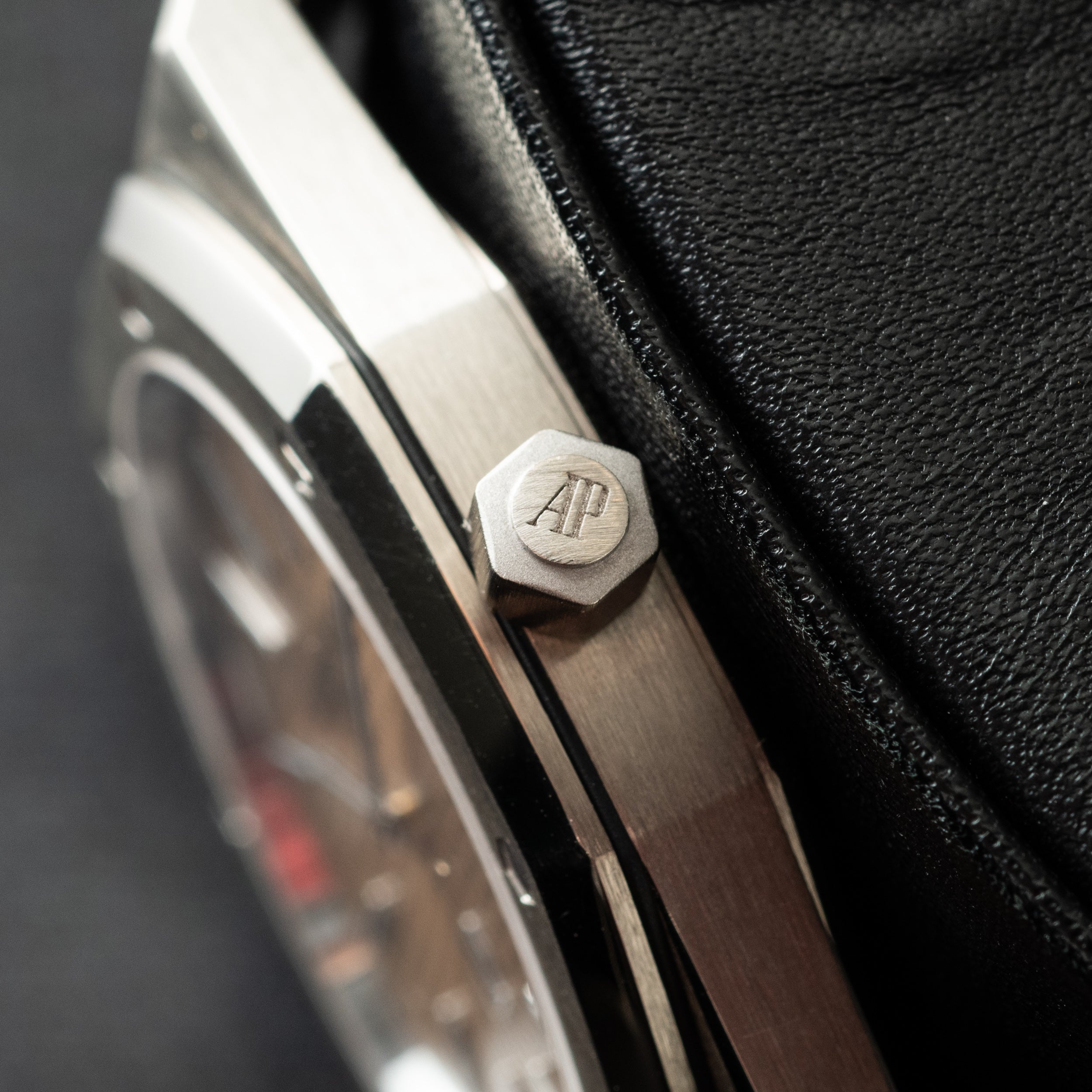 Hexagonal steel case back with AP logo engraving, part of luxury watch shown against black textile.