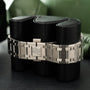 Stainless steel watch bracelet with integrated links and rectangular clasp displayed on black fabric rolls.
