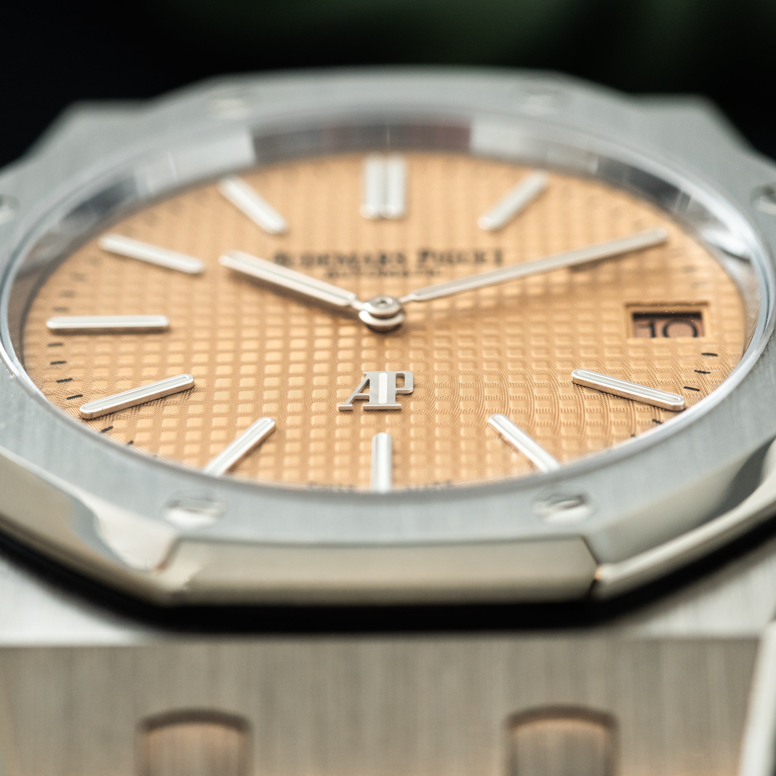 Stainless steel watch with salmon-colored dial, white hour markers, date window, and octagonal bezel.