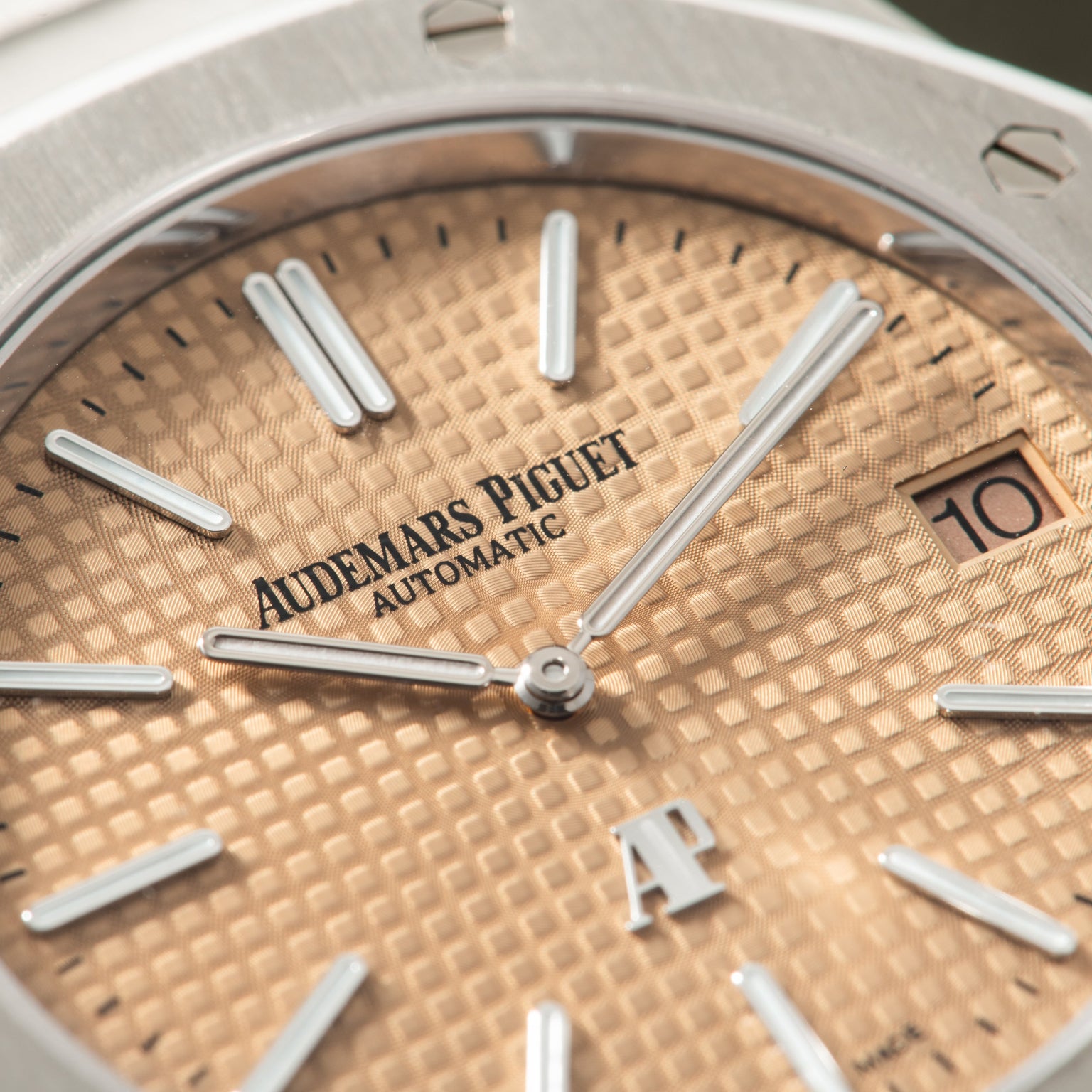 Audemars Piguet Royal Oak automatic watch with salmon-colored dial, silver hands, and date window at 3 o'clock.