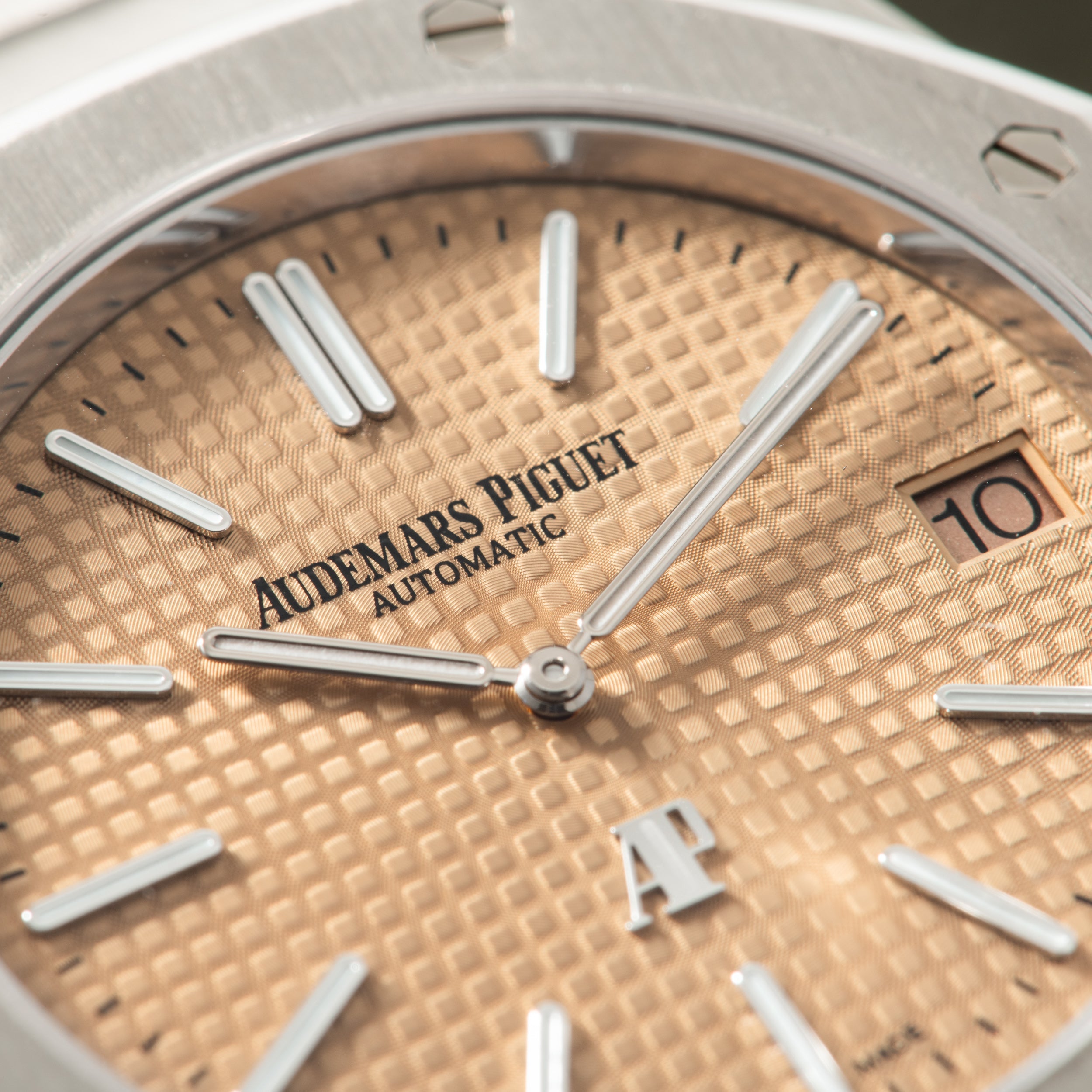 Audemars Piguet Royal Oak automatic watch with salmon-colored dial, silver hands, and date window at 3 o'clock.