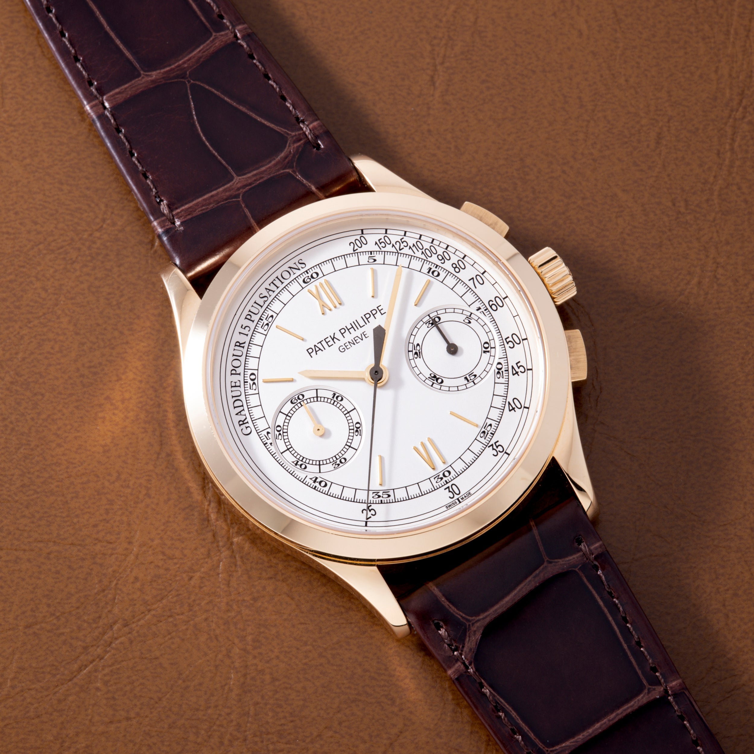 Gold-tone chronograph watch with white dial, Roman numerals, subdials, and dark purple crocodile leather strap.
