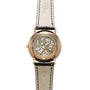Rose gold watch with skeleton caseback displaying mechanical movement, cream leather strap with black stitching.