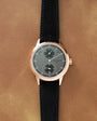 Patek Philippe wristwatch with rose gold case, grey dial, two subsidiary dials, and black leather strap.