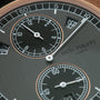 Slate gray watch dial with regulator layout, center hour hand at 3, subsidiary dials with rose gold bezels, "SEP" date window