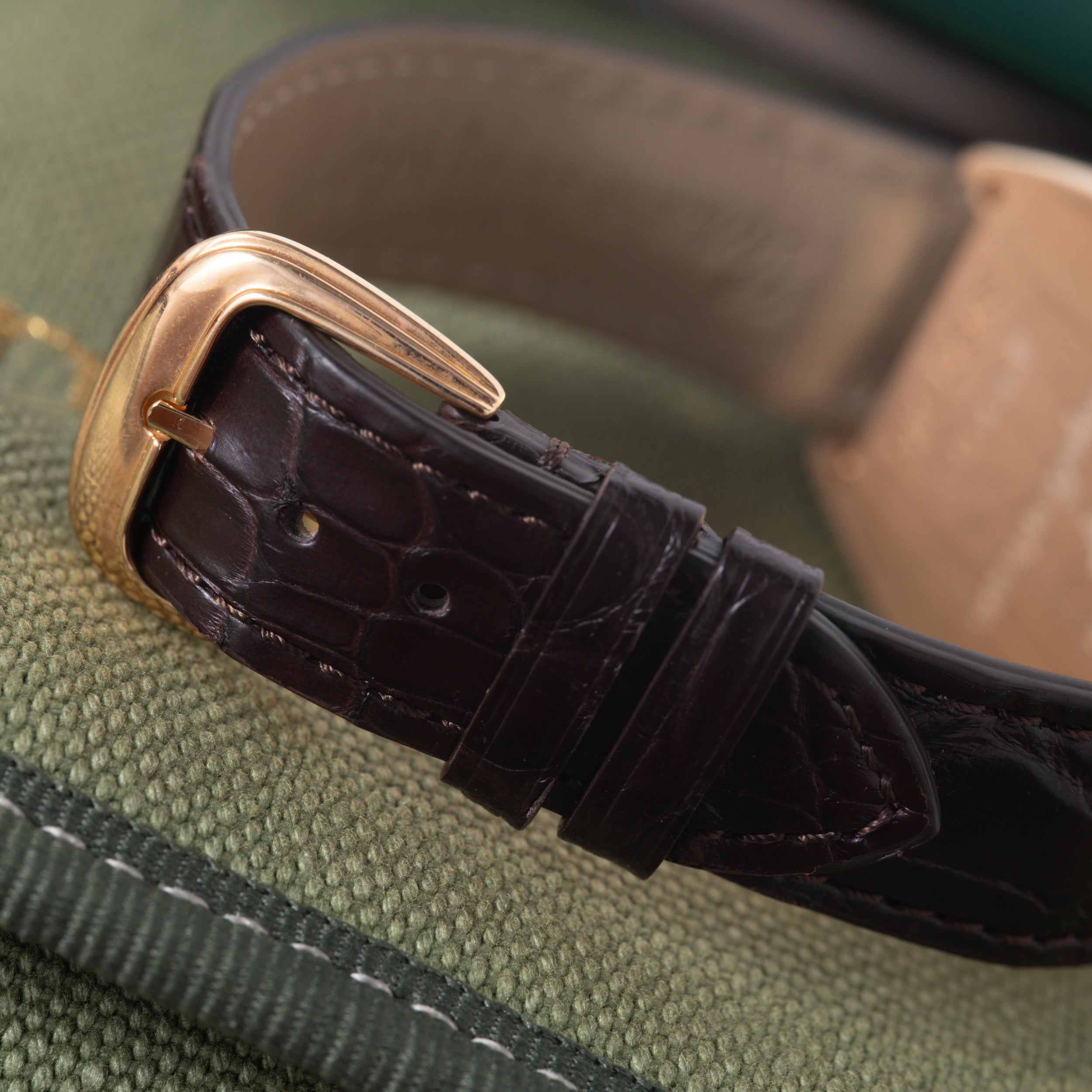 Rose gold rectangular watch case with black crocodile leather strap and gold buckle, displayed on wrist.