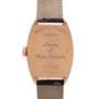 Rose gold tonneau watch case with engraved Franck Muller branding and beige leather strap with black accents.