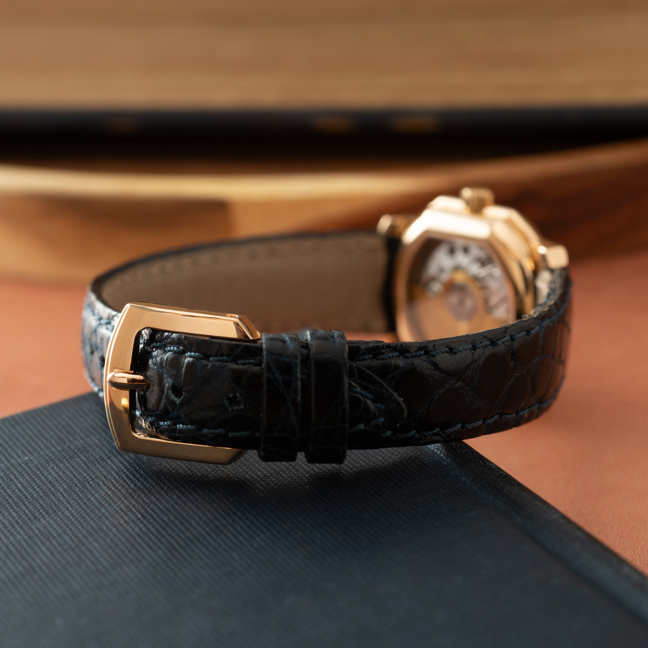 Rose gold-tone watch with white dial and black crocodile leather strap with gold buckle.