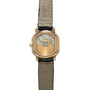 Gold-tone square watch with visible mechanical movement through transparent caseback, black and gray leather strap.
