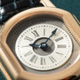 Rose gold watch with cream dial, Roman numerals, blue hands, and "Daniel Roth" text visible on bezel.