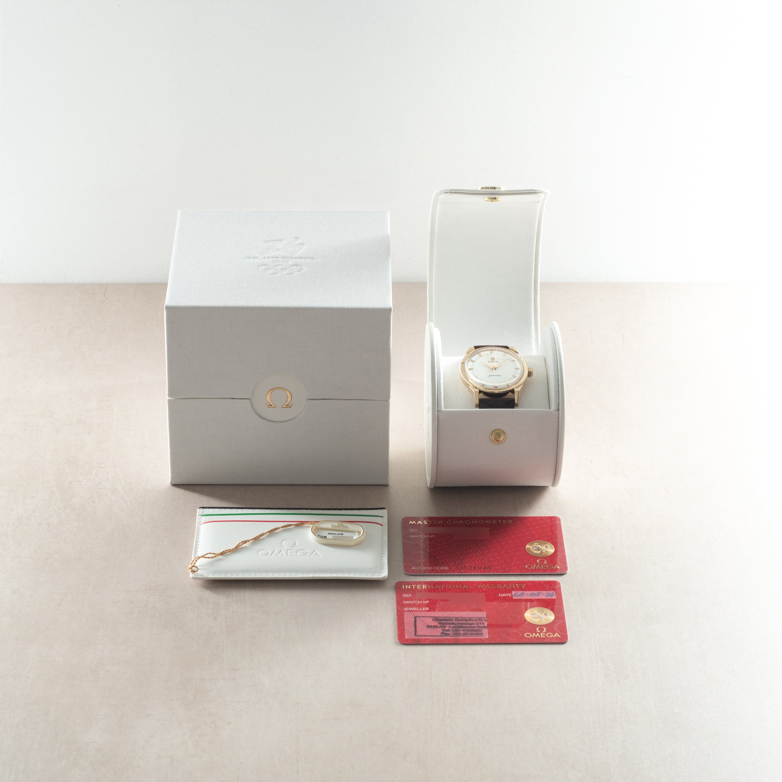 Omega Milano Cortina watch with rose gold case and white dial, displayed with white box, documentation cards, and bracelet st