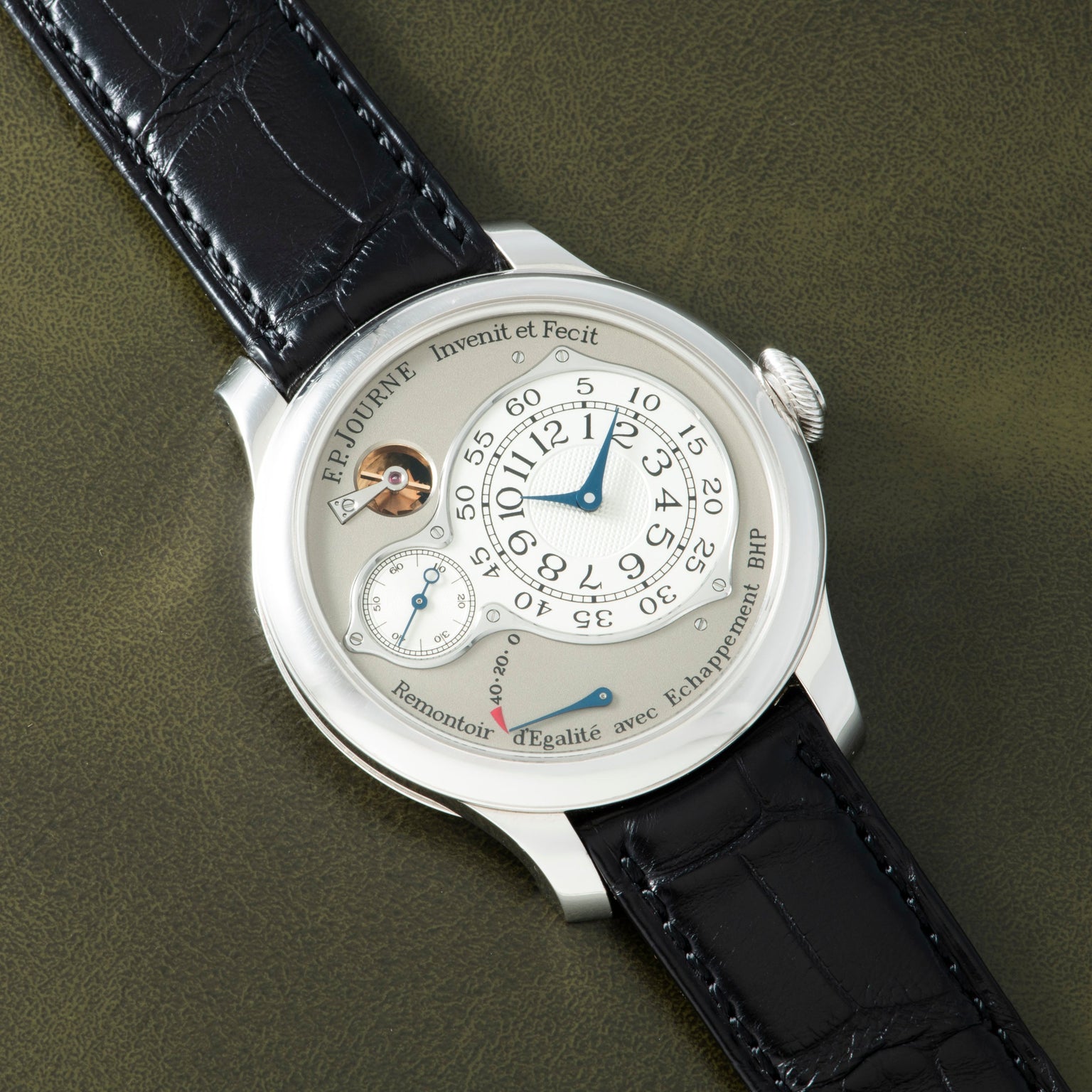 White watch with cream dial, Arabic numerals, blue hands, subsidiary seconds dial, power reserve indicator, and black crocodi