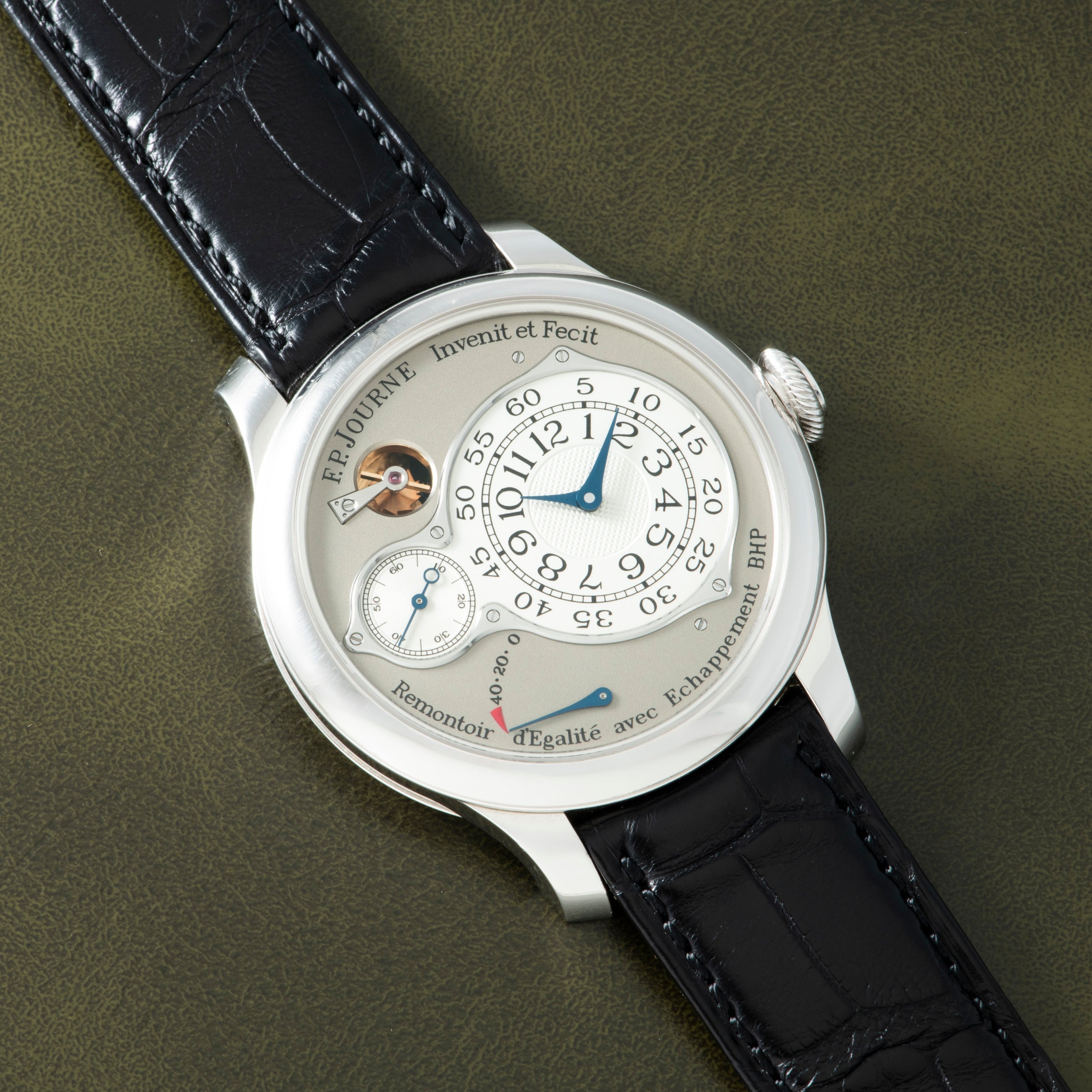 White watch with cream dial, Arabic numerals, blue hands, subsidiary seconds dial, power reserve indicator, and black crocodi