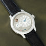 White watch with cream dial, Arabic numerals, blue hands, subsidiary seconds dial, power reserve indicator, and black crocodi