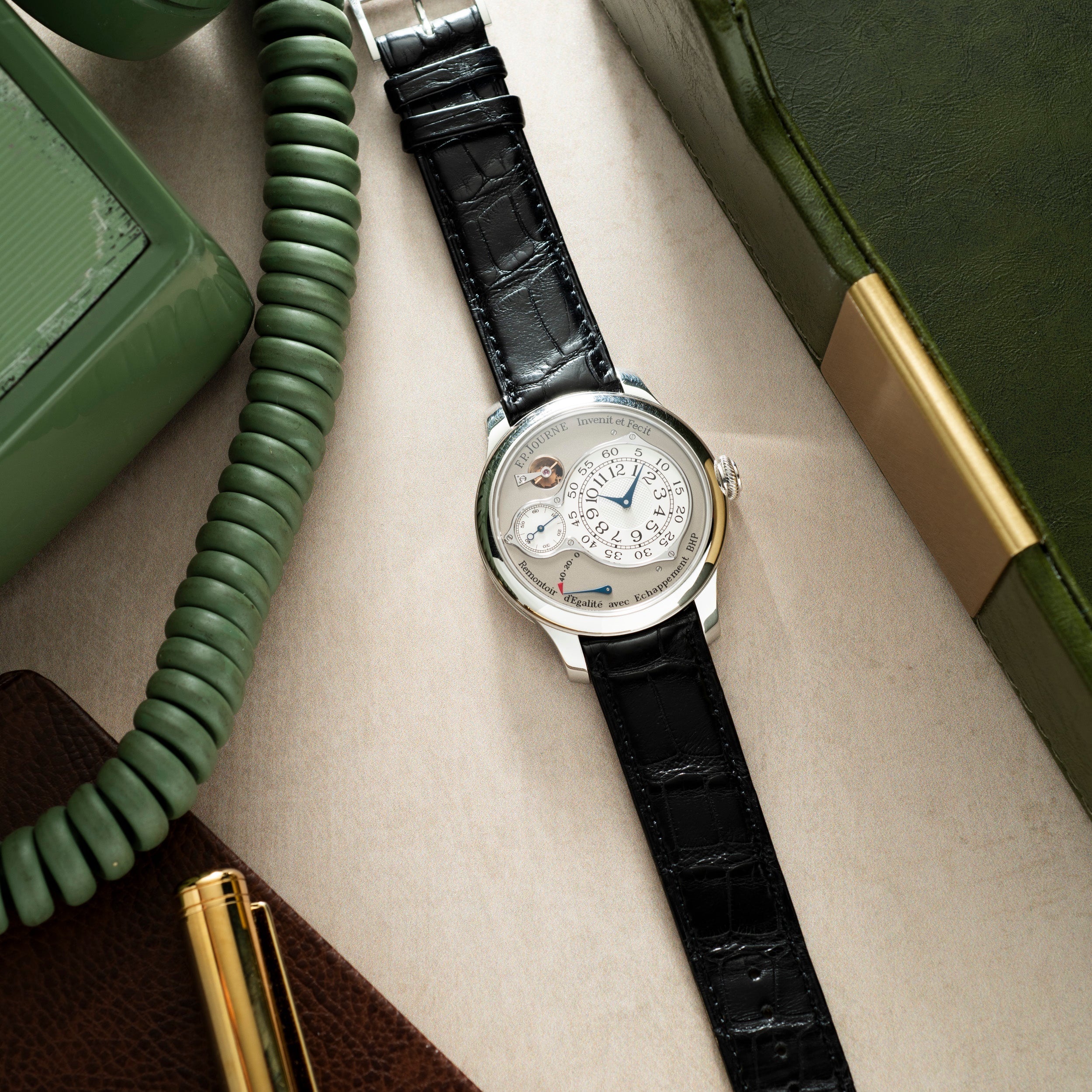 Silver-tone watch with white dial, multiple subdials, and black crocodile leather strap on neutral fabric background.