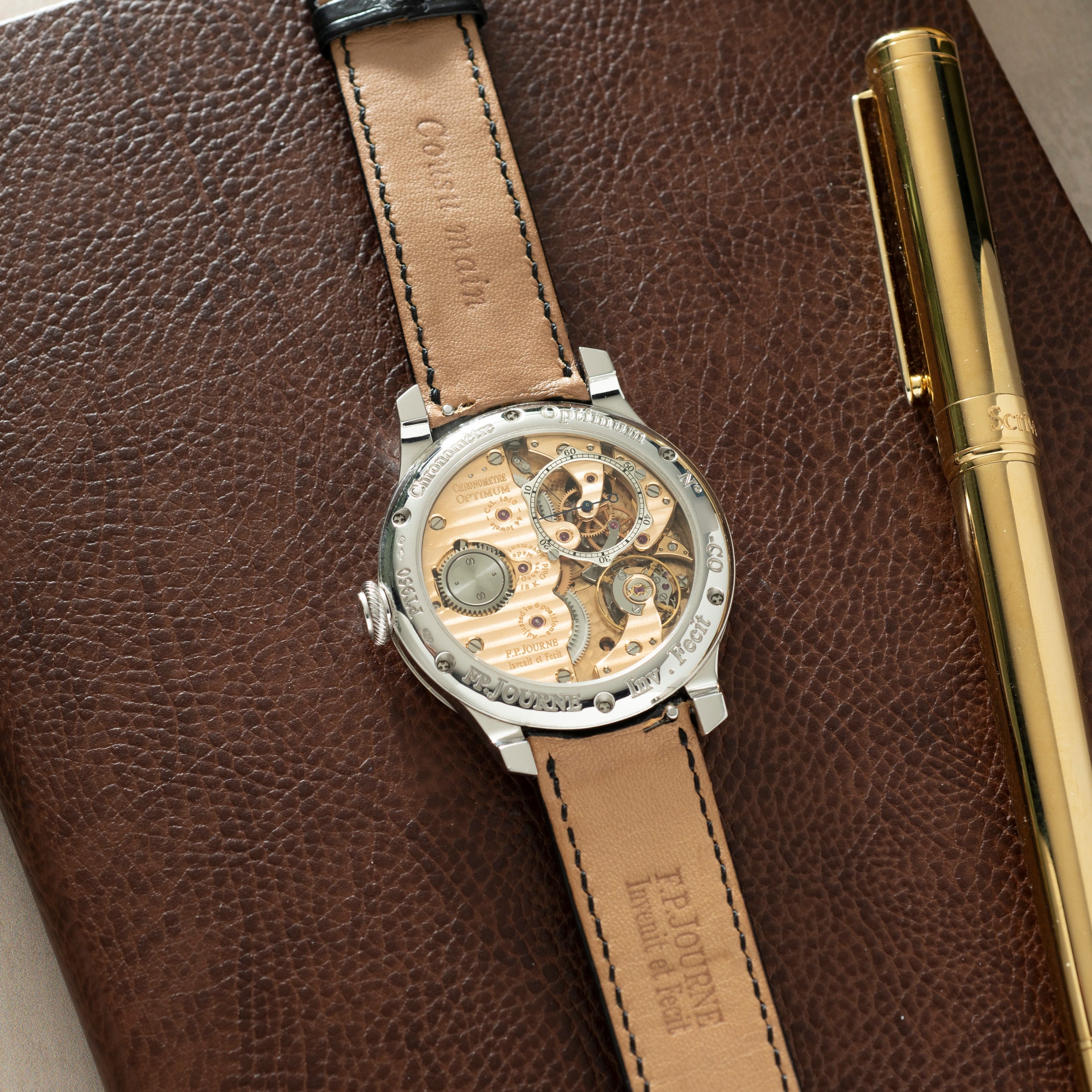 Stainless steel watch with skeleton dial showing exposed movement, tan leather strap with contrasting stitching, displayed on