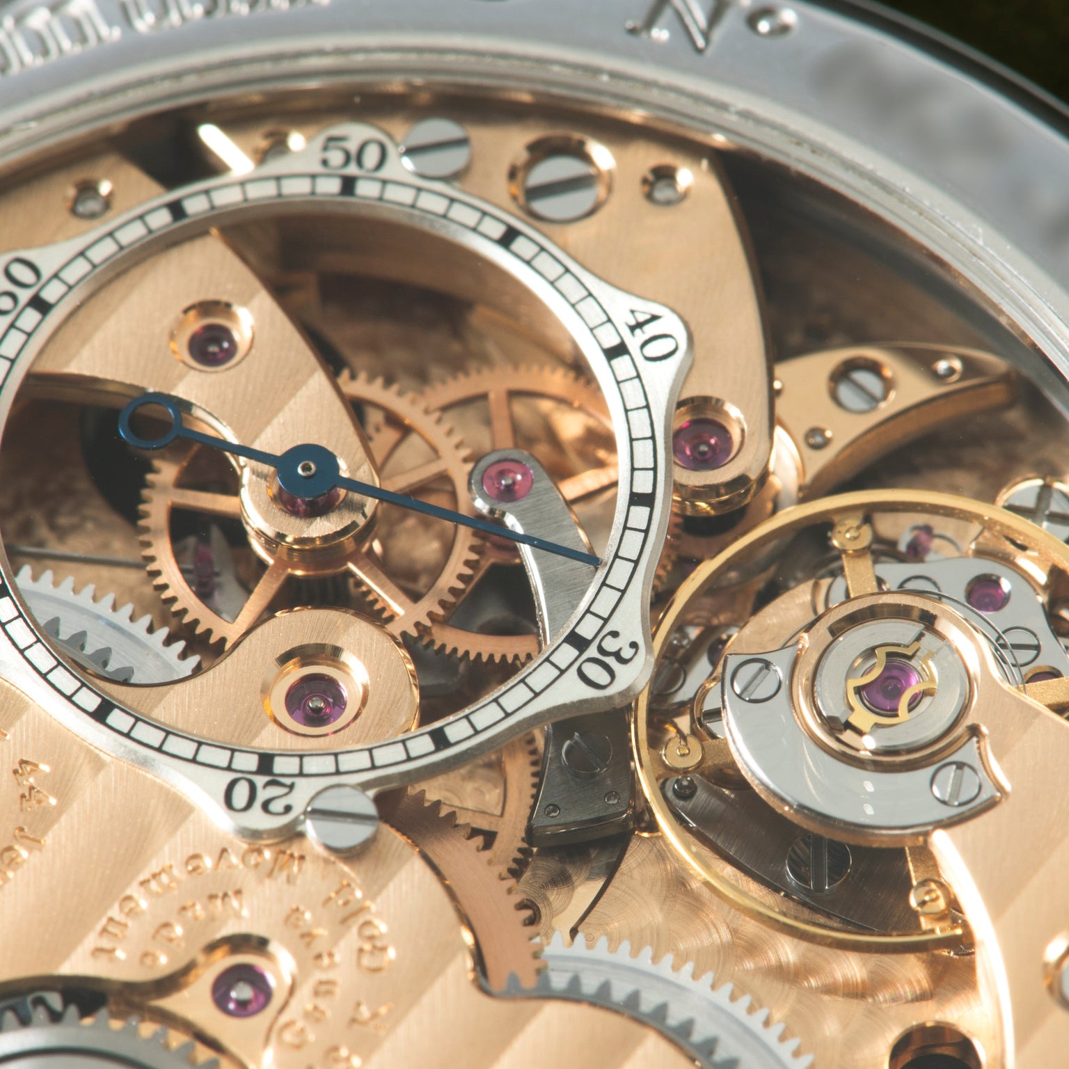 Luxury watch dial with exposed rose gold movement, blue hands, numbered chronograph subdials, and purple jeweled components v