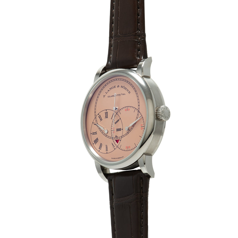 Silver-tone watch with pink dial, Roman numerals, subsidiary dials, and dark brown leather strap.