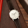 Universal Genève Jumbo Compax chronograph watch with cream dial, black leather strap, and stainless steel case on wood surfac