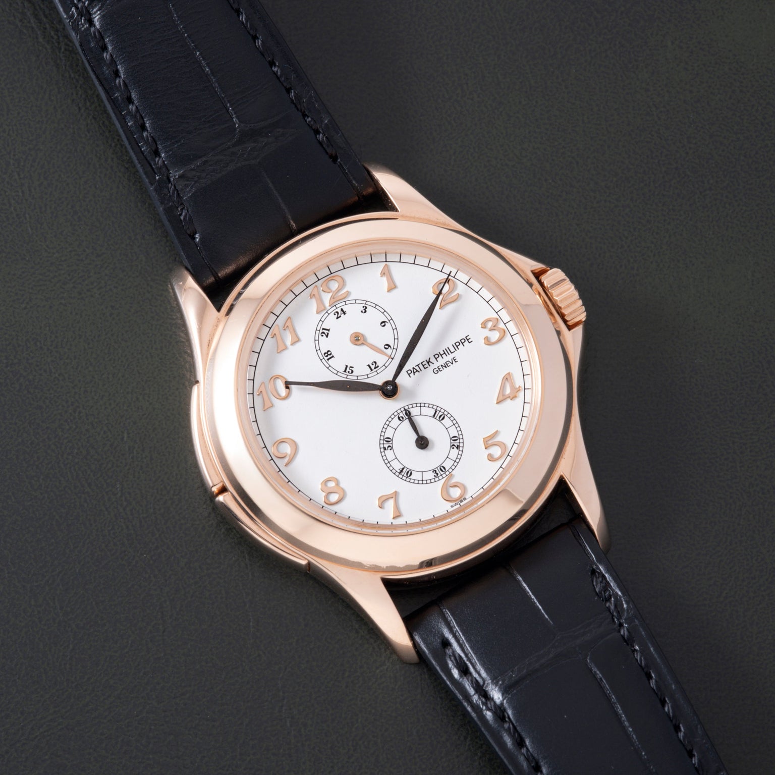 Rose gold round watch with white dial, Arabic numerals, two subdials, and black crocodile leather strap.