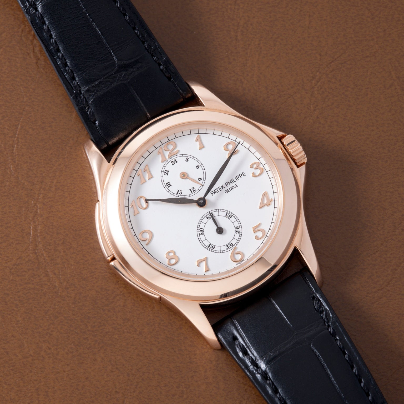 Rose gold watch with white dial, Arabic numerals, two subdials, and black crocodile leather strap.