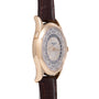 Rose gold watch with cream dial featuring world city names around outer ring and dark leather strap.