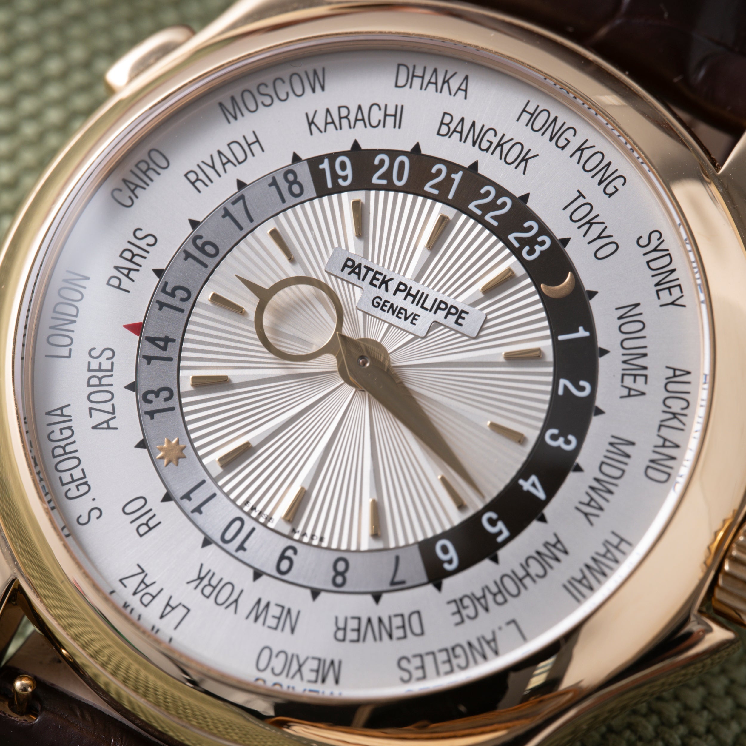 Patek Philippe World Time watch with white dial, city ring, and 24-hour GMT bezel on dark leather strap.