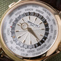 Patek Philippe World Time watch with white dial, city ring, and 24-hour GMT bezel on dark leather strap.