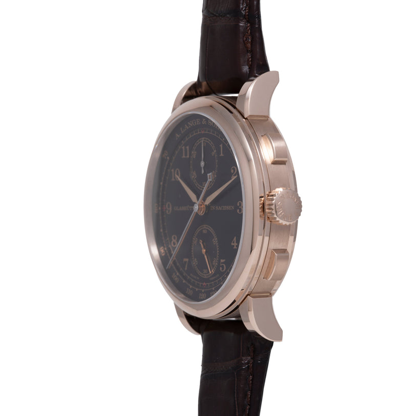 Platinum watch with dark dial, dual chronograph subdials, Arabic numerals, rose gold hands, and dark leather strap.