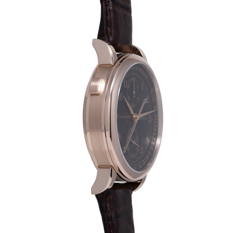 Rose gold chronograph watch with black dial, rose gold hands, and dark brown leather strap.